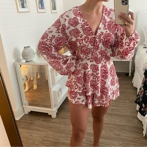 Red and white long sleeve paisley romper with ruffled bottom and tie back